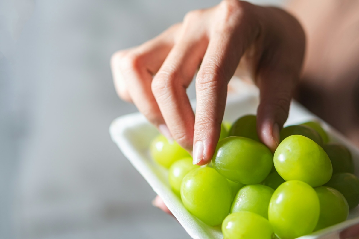 Hand Reaching for Fresh Green Grapes