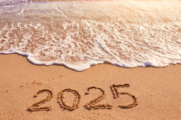 2025 year written on sandy beach sea at sunny day