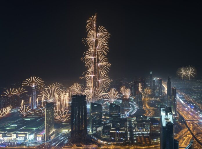 Cityscape of Dubai, United Arab Emirates at night, with fireworks and illuminated skyscrapers.