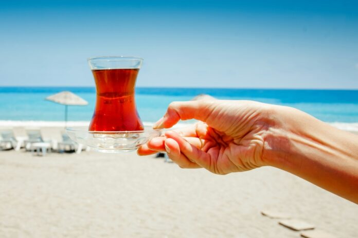 Traditional Turkish black hot tea on beautiful sandy beach background