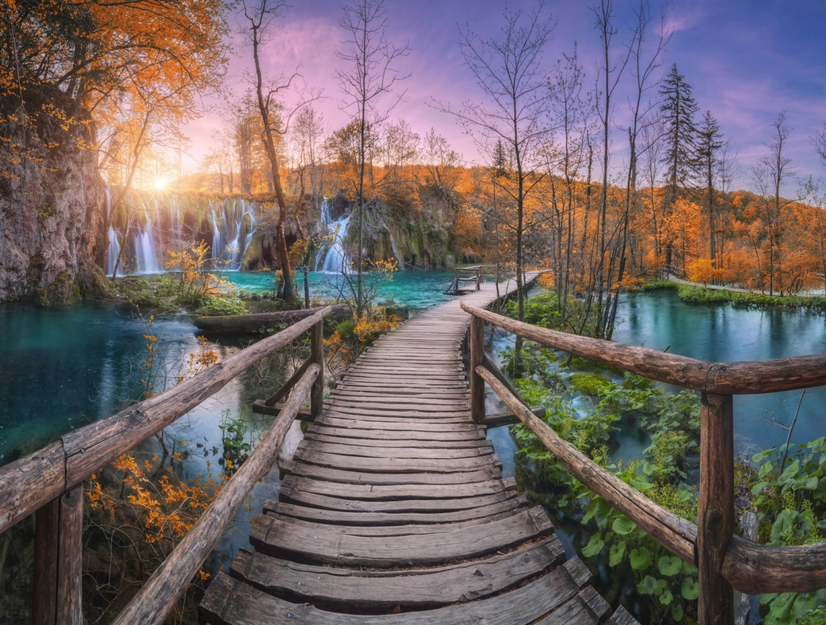 Waterfall and wooden path in orange forest in Plitvice Lakes