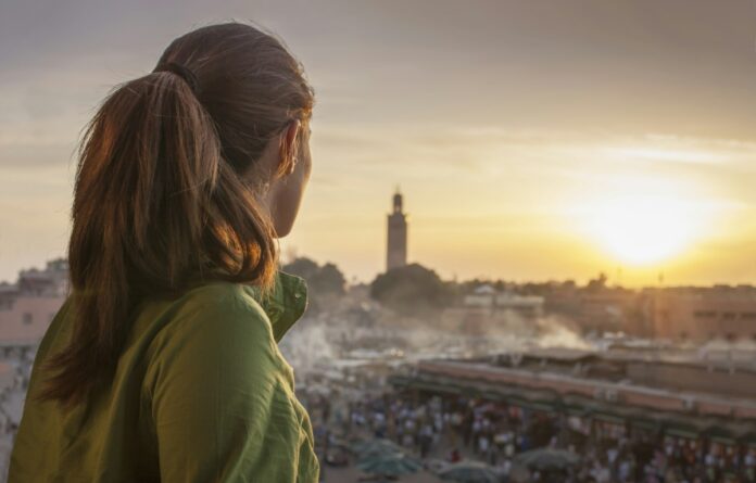 Rear view of woman looking at sunset over Jemaa el-Fnaa Square, Marrakesh, Morocco