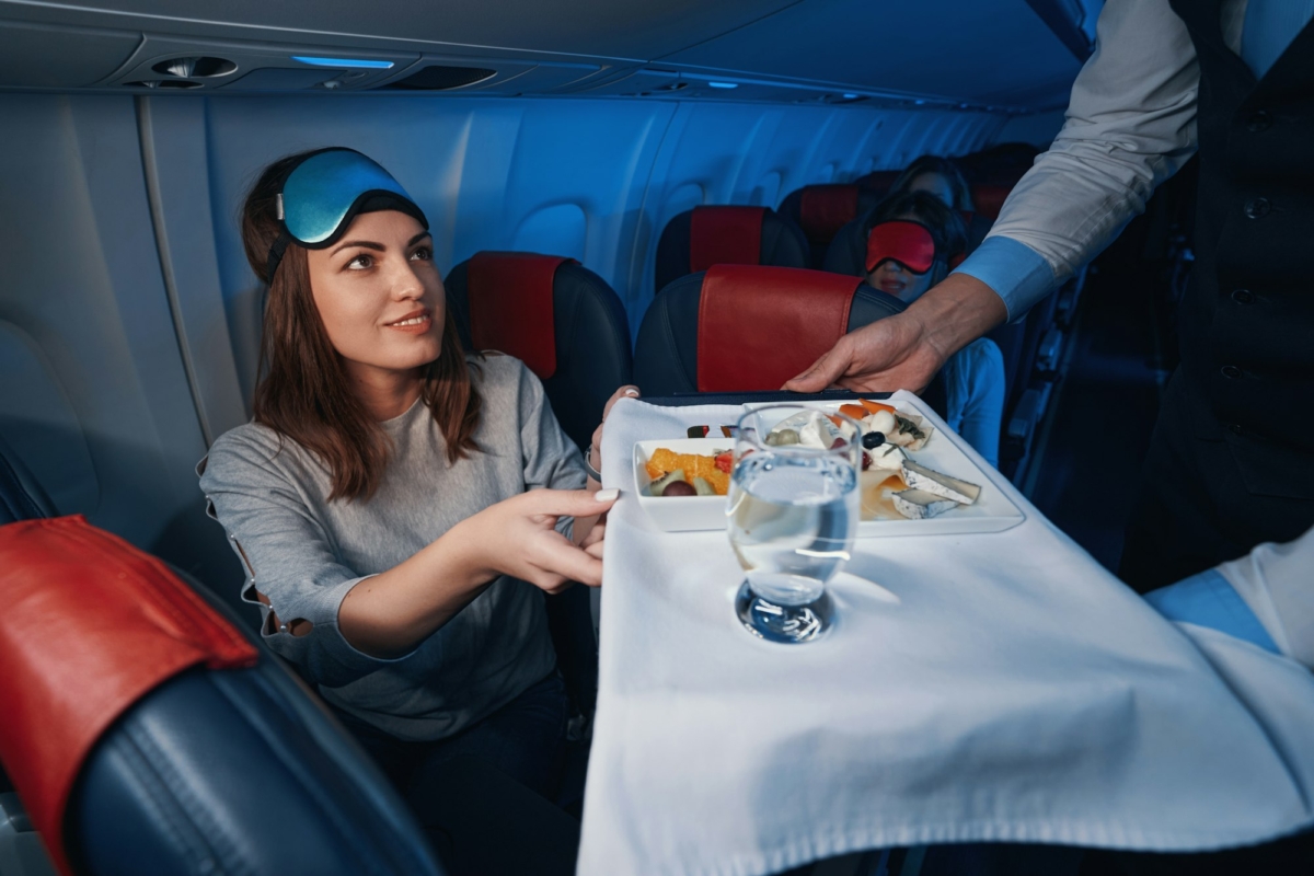 Woman passenger receiving in-flight food from airline steward