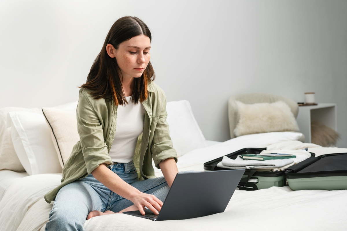 Young brunette woman makes an online reservation on her laptop at the last minute before her trip.