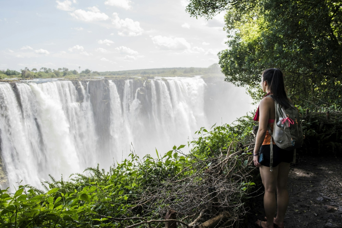 Young female tourist looking out at Victoria Falls, Zimbabwe, Africa