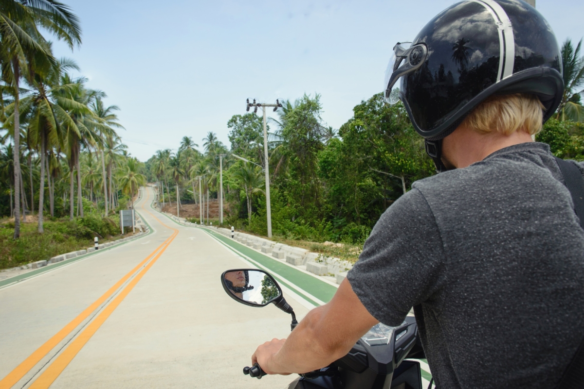 View on the highway from the point of driver of scooter. Back of the tourist on the road in Thailand